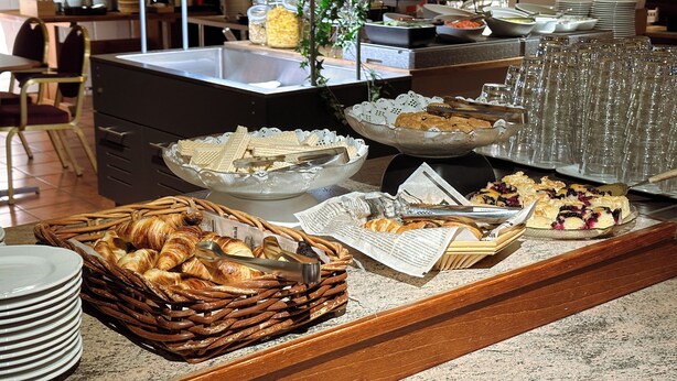 A buffet setup with various food items, including pastries and a fruit display. - Hotel Sommelo (Kouvola)