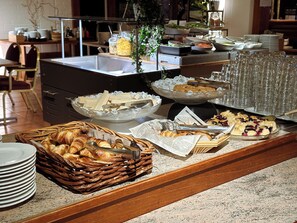 A buffet setup with various food items, including pastries and a fruit display. - Hotel Sommelo (Kouvola)