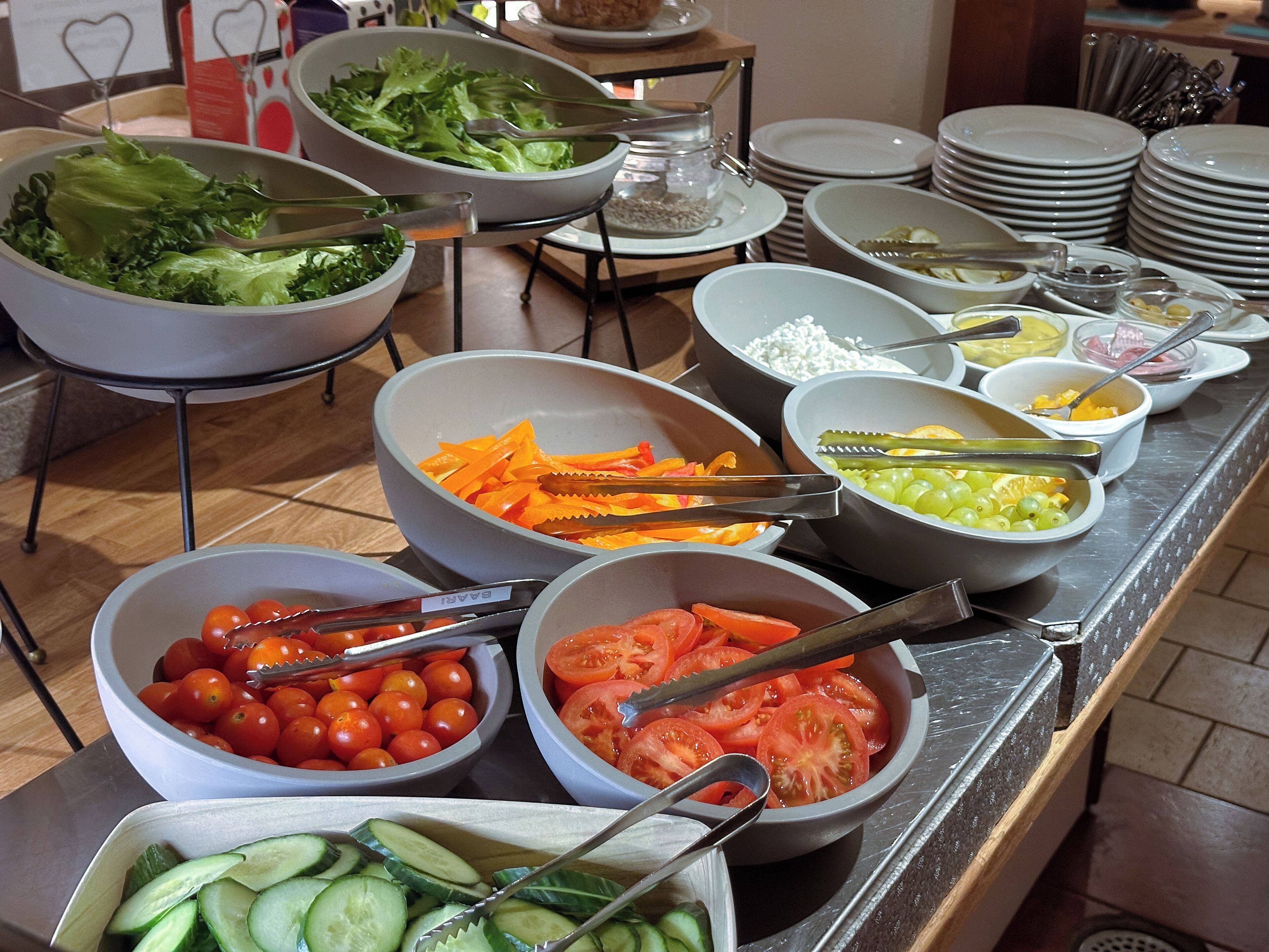 Un buffet con diverse pietanze, tra cui verdure, frutta e cereali.
