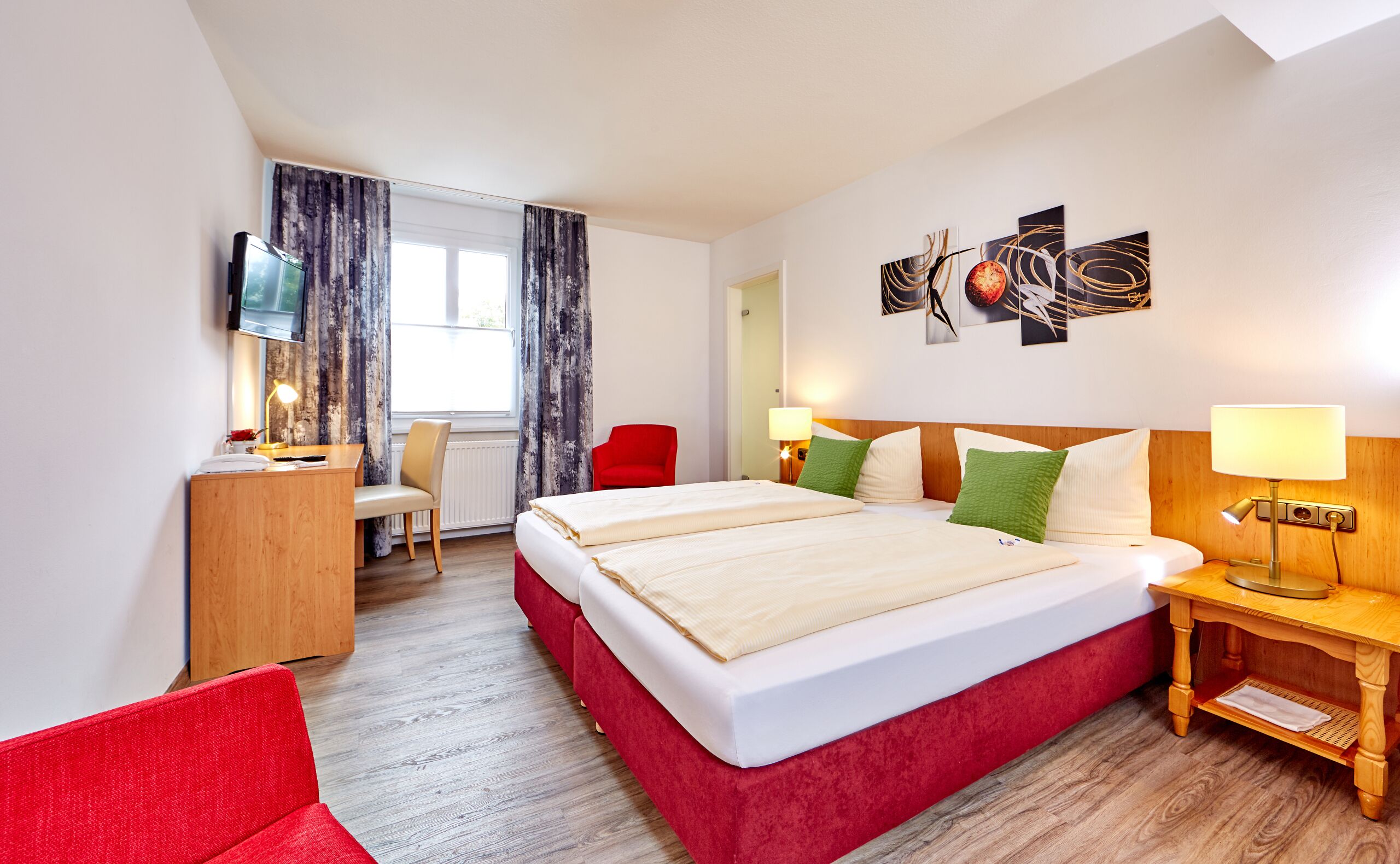Habitación de hotel con una cama, dos mesitas de noche, un escritorio, una silla, televisión y una obra de arte en la pared.