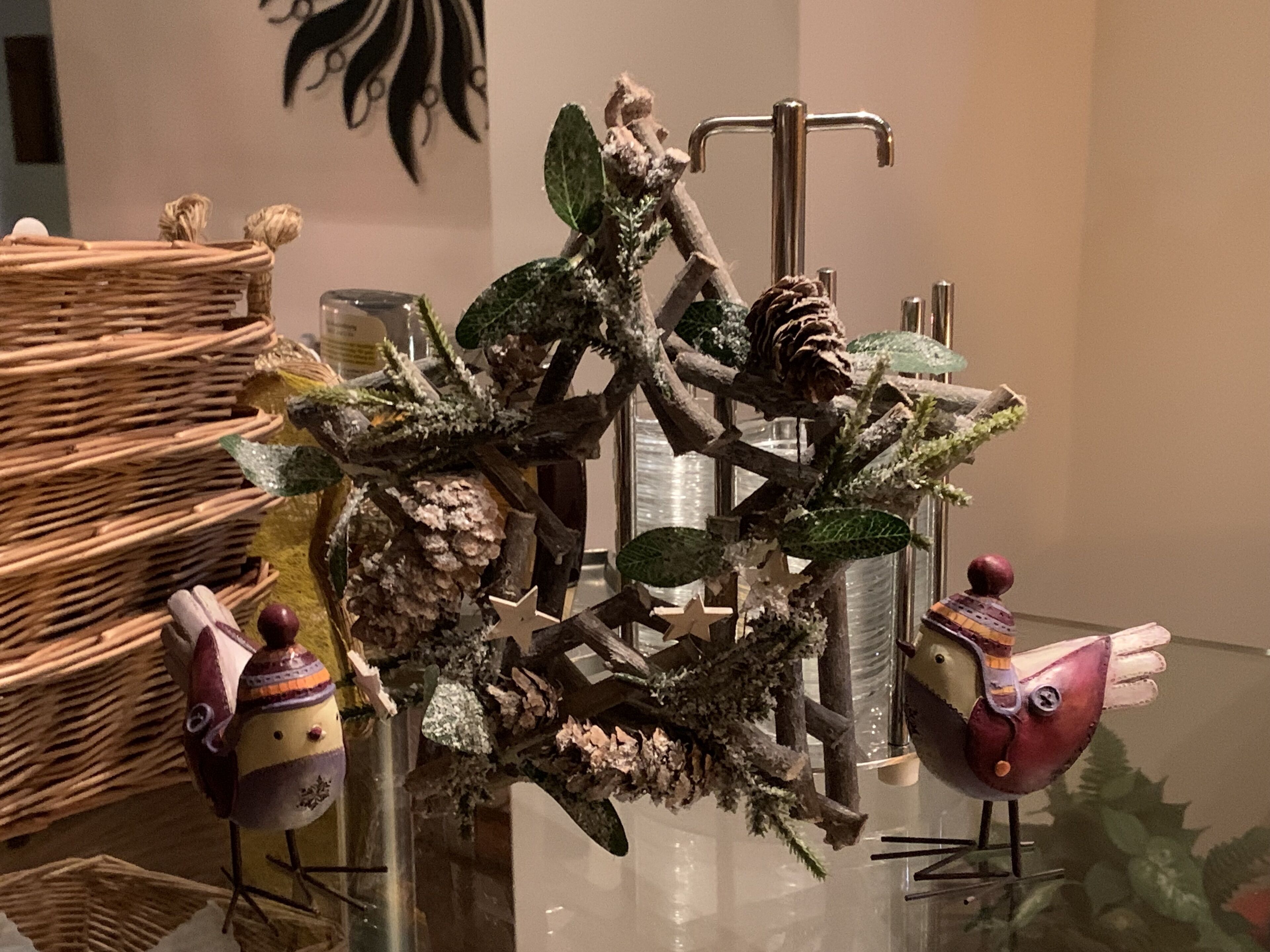 A decorative indoor setting with a rustic wooden structure, possibly a piece of art or a display, surrounded by various objects including a bird figurine and a woven basket.