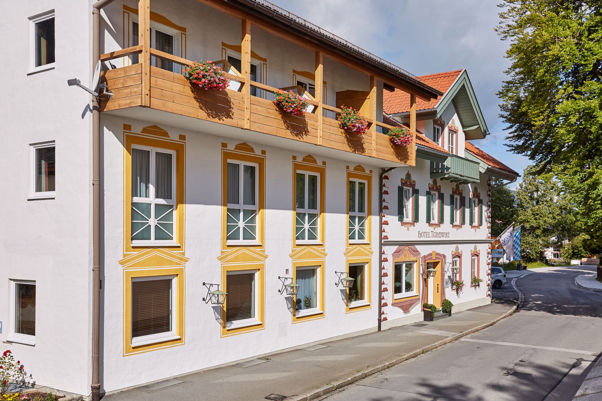 A traditional building with multiple windows, balconies with flower boxes, and a sign indicating it is a hotel.