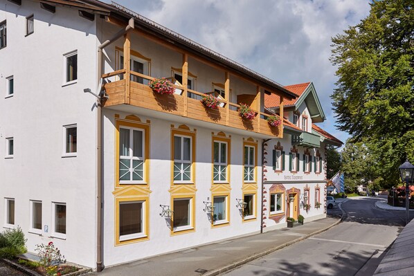 A traditional European hotel with multiple balconies, large windows, and a classic facade. - Zum Turm - Apartments und Gästezimmer (Oberammergau)