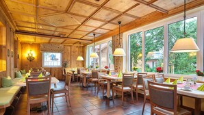 Un restaurante con interior de madera, ventanas amplias y varias mesas y sillas.