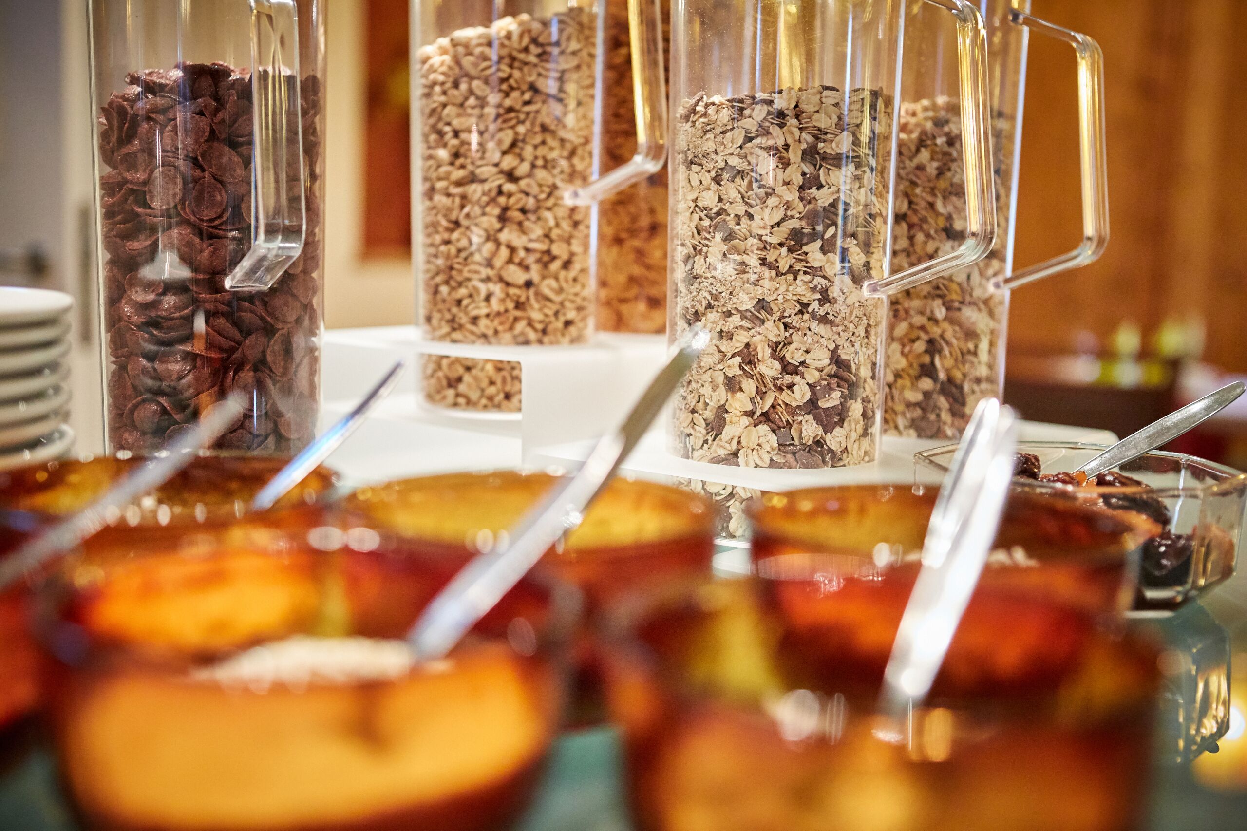 A buffet with various food items in clear containers, including cereal and snacks.