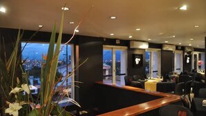 Un restaurant doté d’une table de billard, de nombreux sièges et de grandes fenêtres donnant sur la ville.