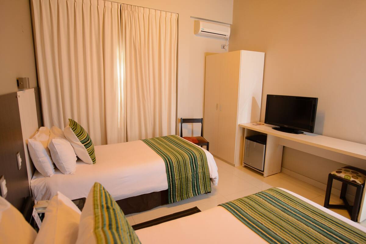 A hotel room with a bed, a desk, a television, and a wardrobe.