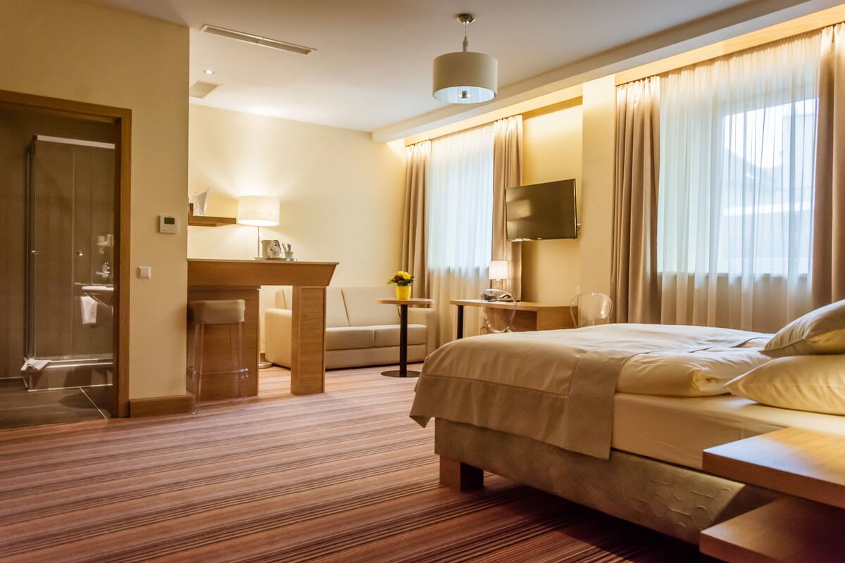 Habitación de hotel con cama, escritorio, silla, televisor y baño.