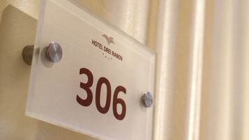 Ein Schild mit der Zimmernummer 306, angebracht an einer Wand mit strukturierter Oberfläche.