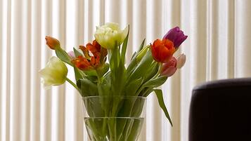 Un florero de vidrio transparente con tulipanes sobre una superficie reflectante.
