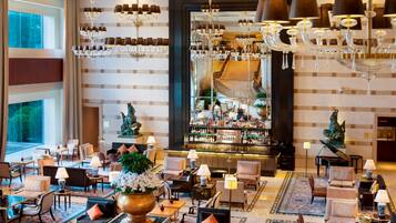 Eine geräumige Lobby mit mehreren Sitzbereichen, einer Bar und einem Klavier.