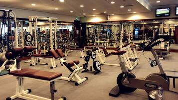 Un gimnasio con varios equipos de ejercicio, incluyendo cintas de correr, máquinas de pesas y pesas libres.