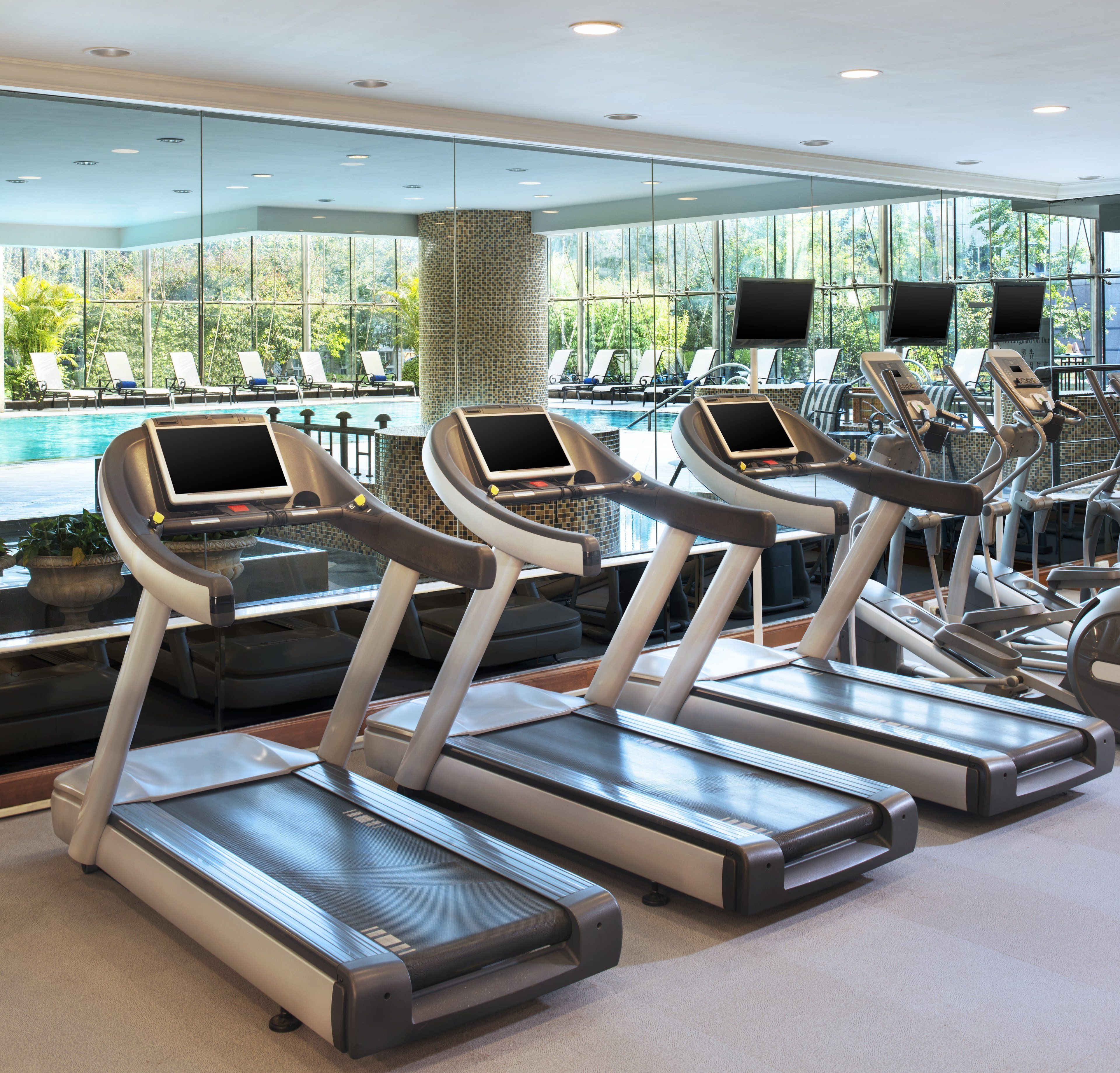 A gym with treadmills, exercise bikes, and a pool area with sun loungers.