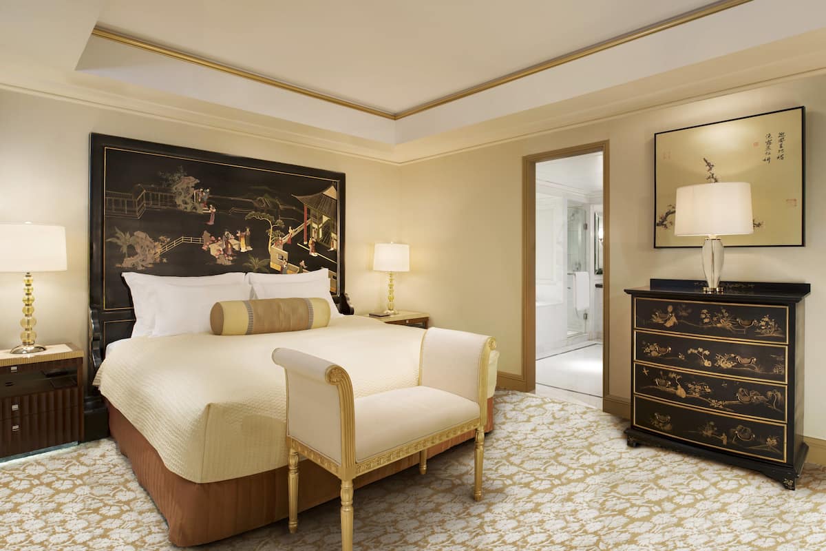 A hotel room with a large bed, two bedside tables, a nightstand, a dresser, and a chair.
