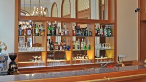 Zona de bar con mostrador de madera, taburetes azules y un espejo grande que refleja el interior.