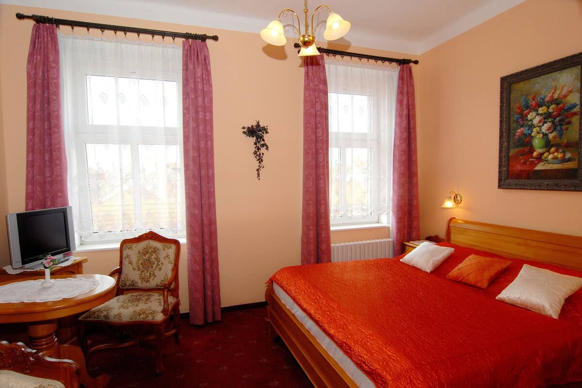 Quarto de hotel com uma cama grande, uma mesa com computador e uma cadeira.