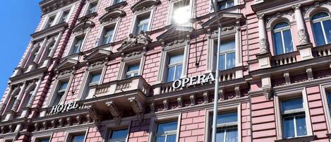 Een roze gebouw met borden waarop 'HOTEL' en 'OPERA' staan.