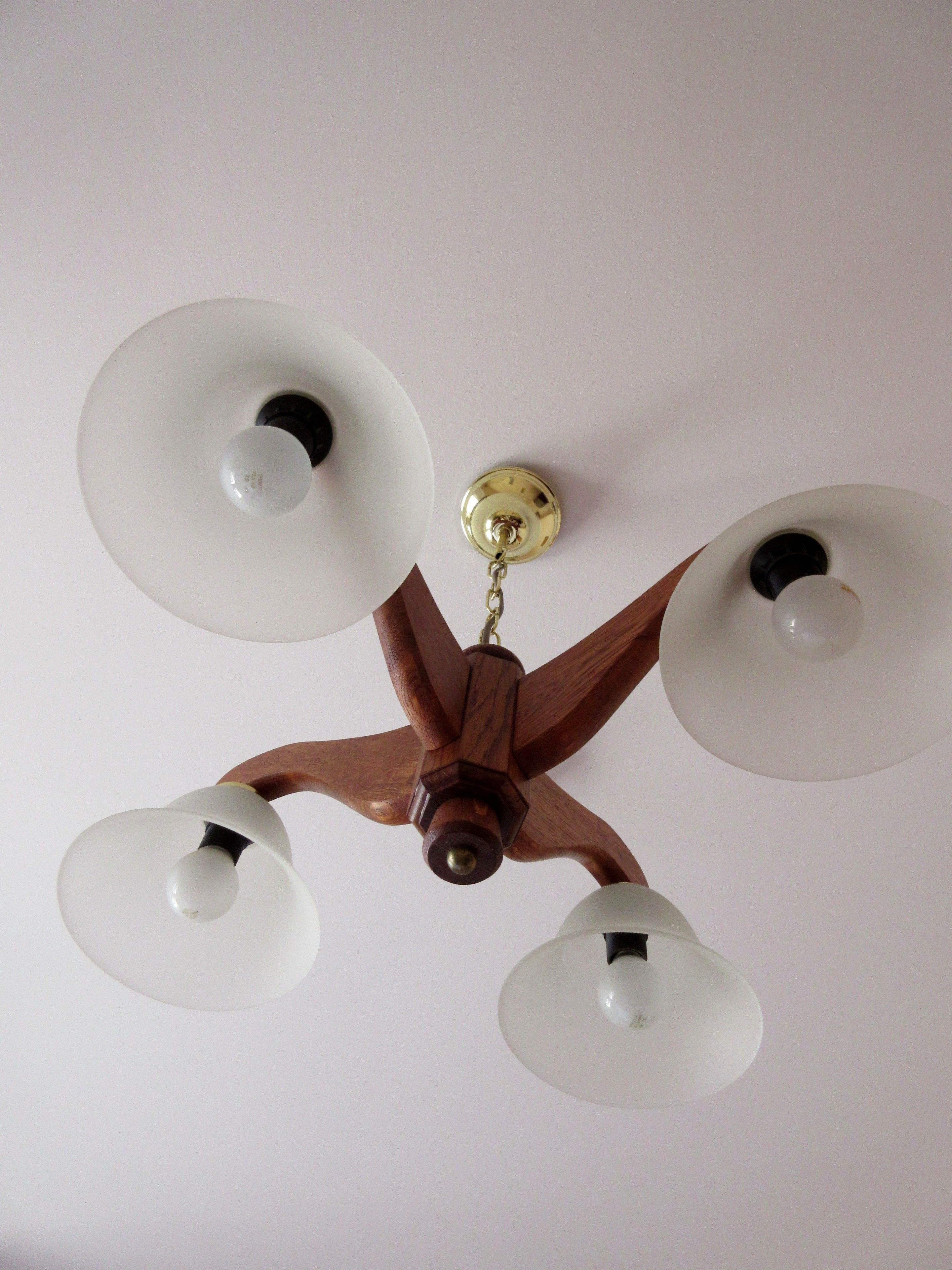 A ceiling fan with five white lampshades and a wooden central structure.