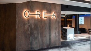 Una moderna zona de recepción con un letrero iluminado grande que dice "OREA" y un mostrador de recepción.