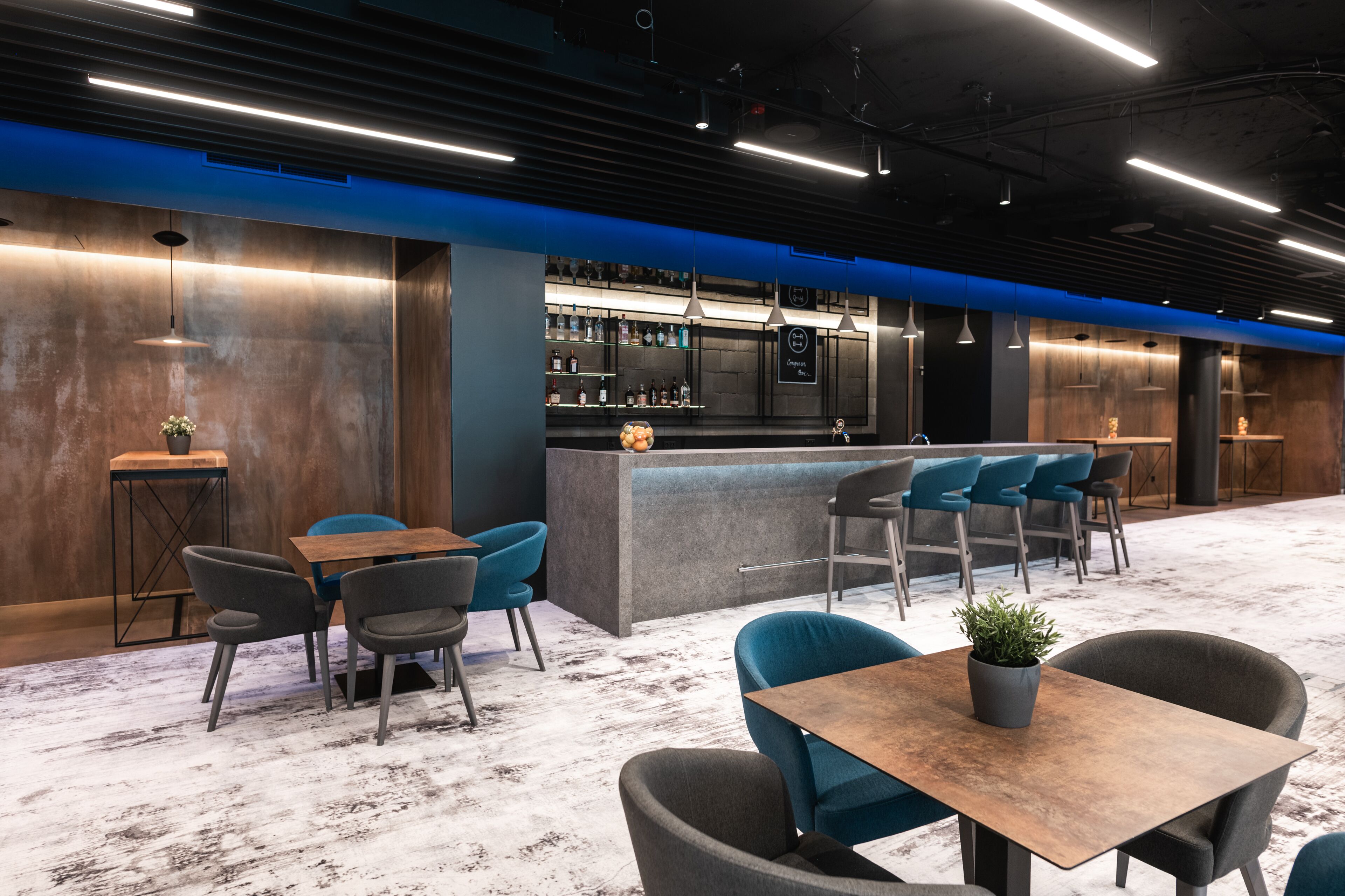 A modern bar area with a bar counter, seating, and a variety of bottles on shelves.