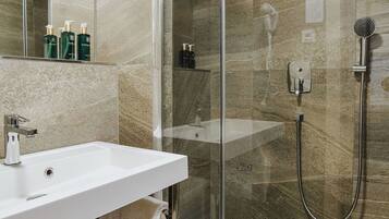 Une salle de bain moderne avec une douche à parois de verre, un lavabo blanc et un porte-serviettes.
