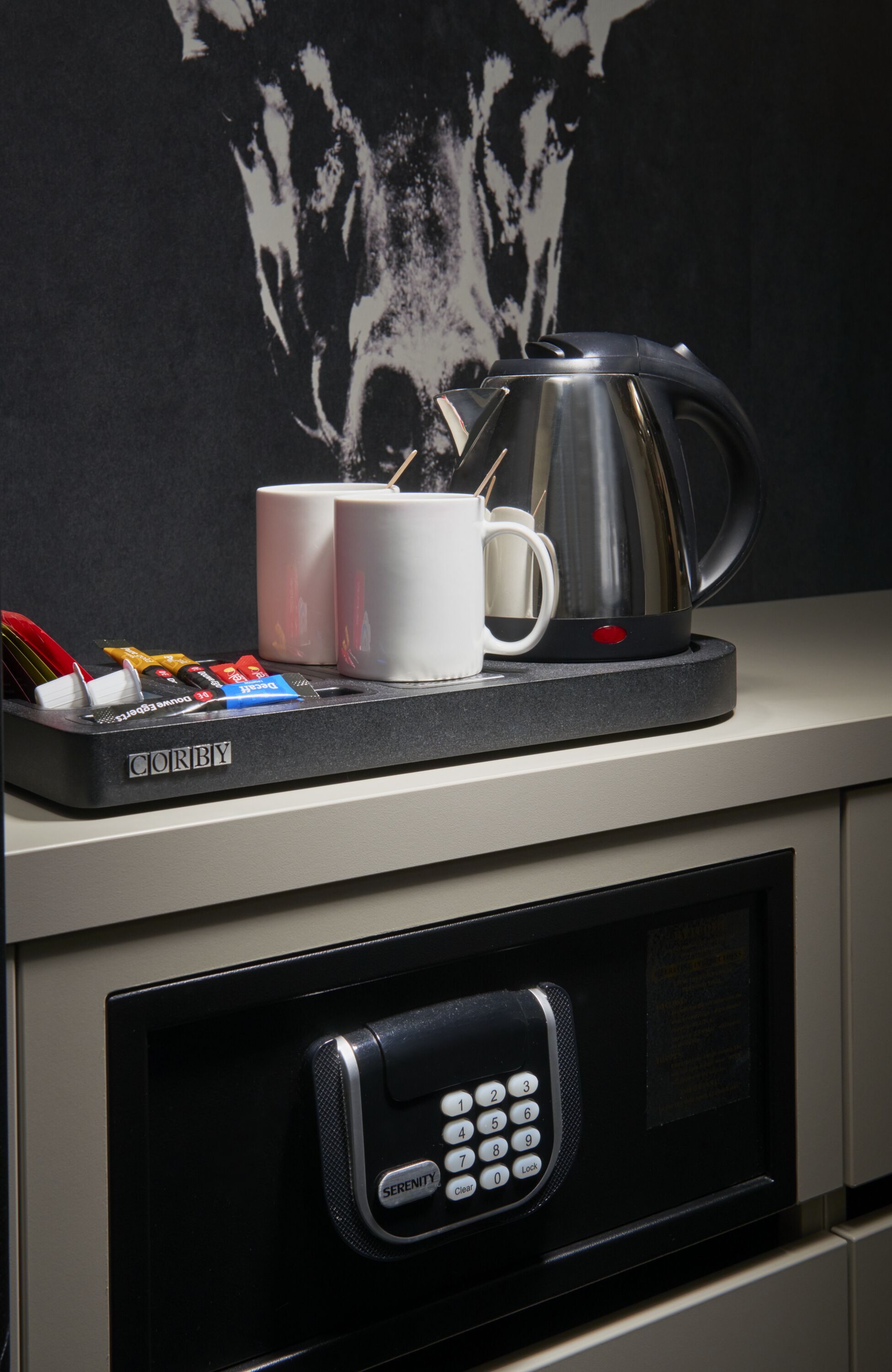 A microwave with a coffee maker and a tray with utensils and condiments on a countertop.