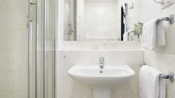 A bathroom with a glass shower enclosure, a pedestal sink, and a mirror above the sink.