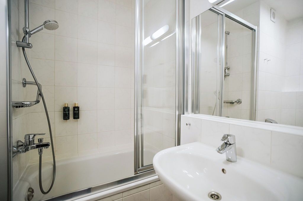 A modern bathroom with a glass-enclosed shower, a white sink, and a mirror.