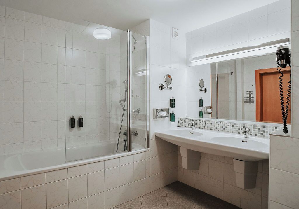A modern bathroom with a glass-enclosed shower, a large vanity with a mirror, and a sink.
