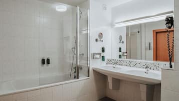 Un baño moderno con cabina de ducha de vidrio, un tocador amplio con espejo y un lavabo.