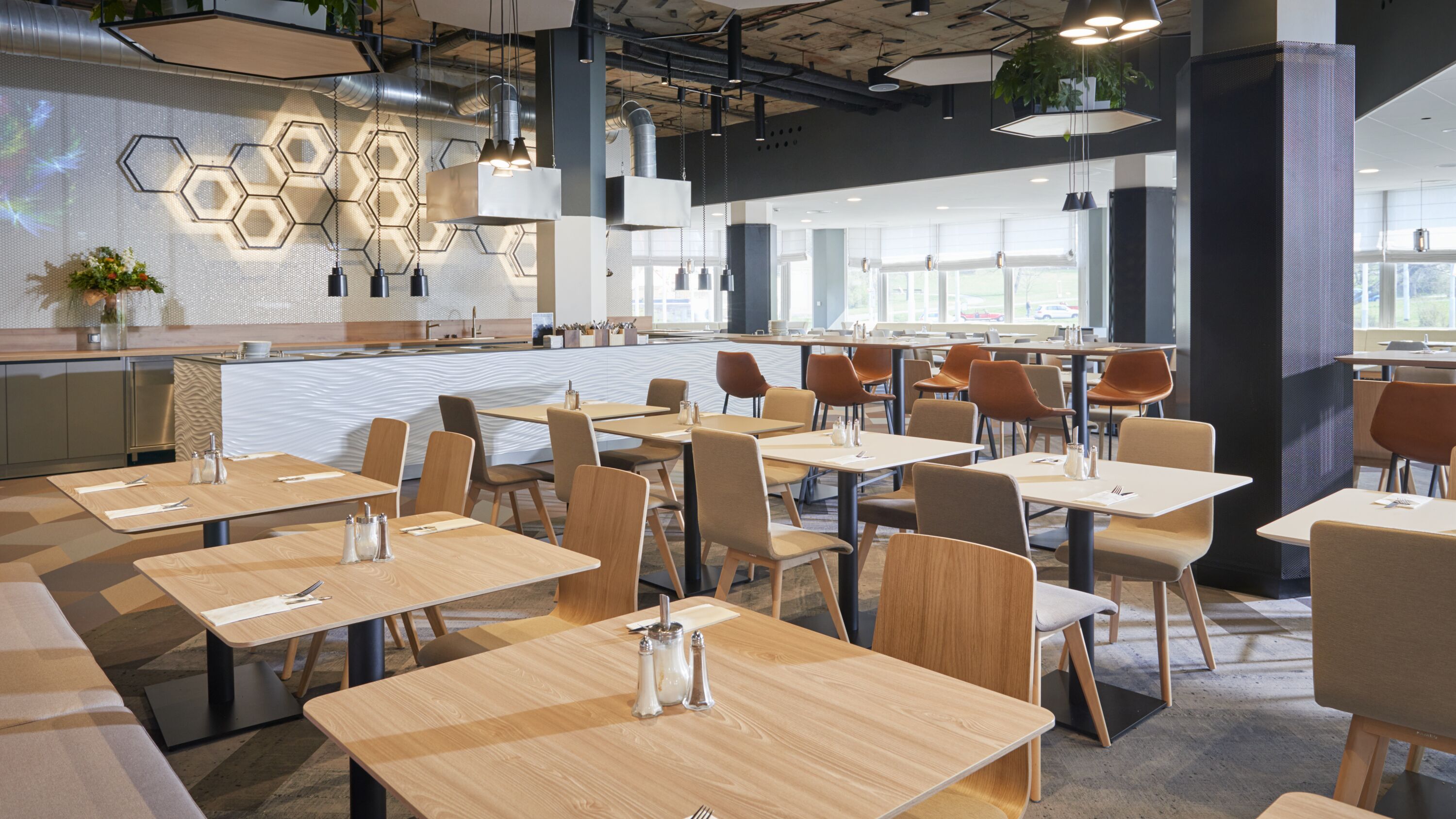 A modern dining area with hexagonal wall decor, wooden tables, and chairs.