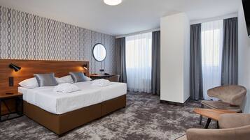 Una habitación de hotel moderna con una cama grande, una mesita de noche, un espejo redondo, un escritorio y una silla.