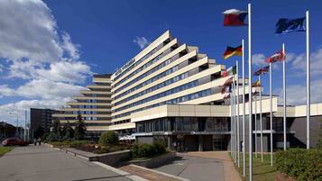 A modern hotel with a unique angular design, multiple flags, and a well-maintained outdoor area.