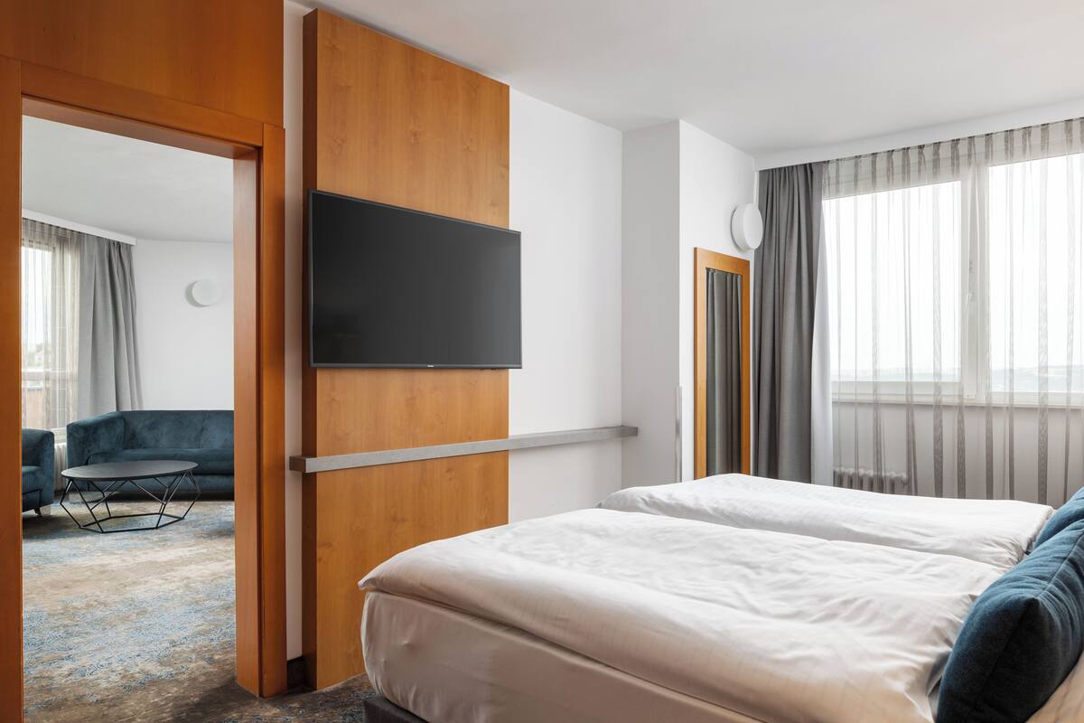 A hotel room with a bed, a TV mounted on the wall, a desk, and a chair.