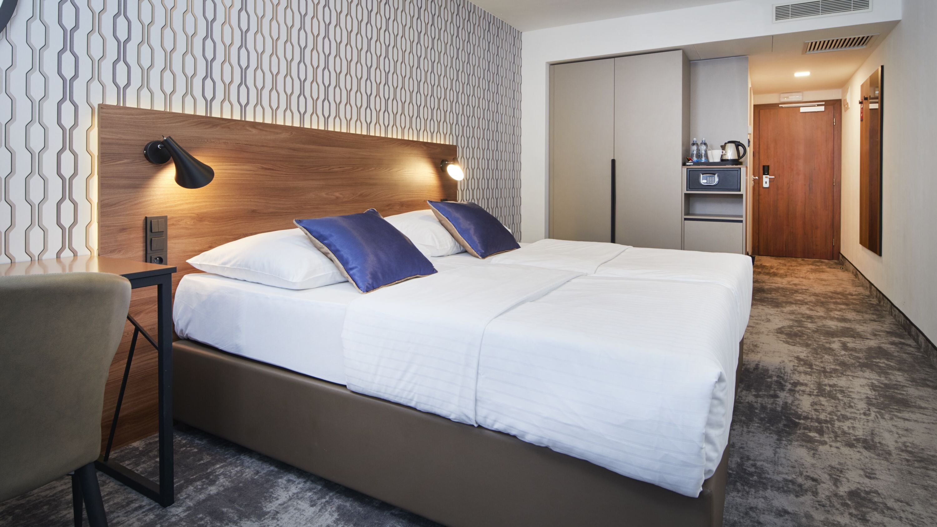 Quarto de hotel moderno com uma cama grande, uma mesa e um guarda-roupa.