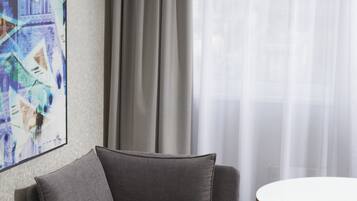 Una habitación moderna con un sofá gris, una mesa redonda y un cuadro abstracto grande en la pared.