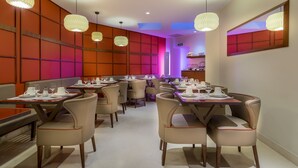 Un restaurante con varias mesas y sillas, cada conjunto con vajilla blanca y vasos.