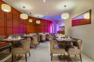 Un restaurante con varias mesas y sillas, cada conjunto con vajilla blanca y vasos.