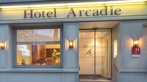 Hotel Arcadie, con un área de recepción visible a través de las puertas de vidrio.