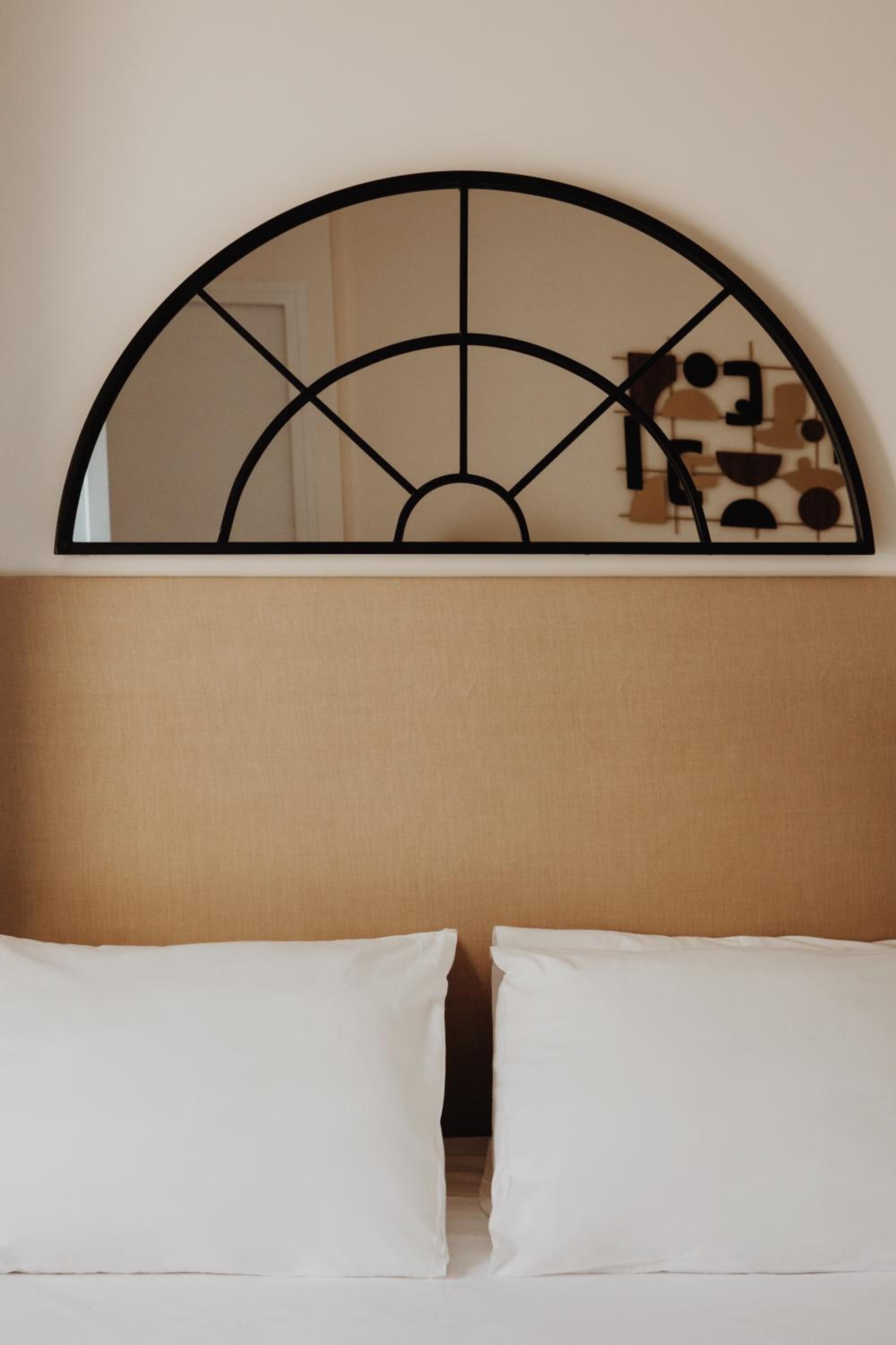 A bed with white linens and a headboard with a geometric design.