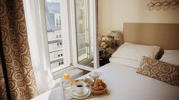 Una habitación de hotel con cama, bandeja de desayuno y una ventana con cortinas.