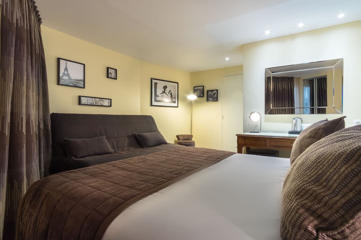 Una camera d'albergo con un letto grande, una scrivania con uno specchio e quadri appesi alle pareti.