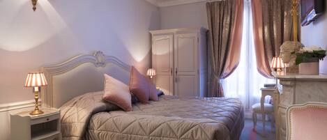 A bedroom with a large bed, a nightstand, a dresser, a chair, and a television on the wall.