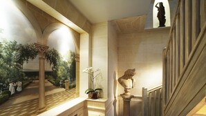 A grand staircase with a balustrade, a bust sculpture, and a potted orchid. - Hôtel & Spa Saint Jacques (Paris)
