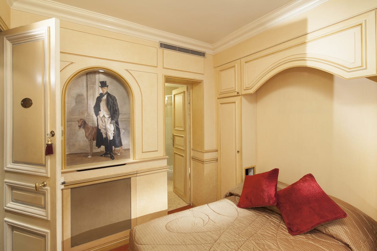 A room with a bed, a mirror, and a door.