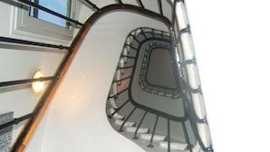 A spiral staircase with a metal handrail and a glass enclosure at the top. - Hôtel Cosy Monceau (Paris)