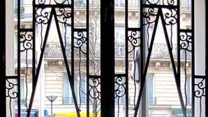 A person walking past a building with ornate metal gates. - Hôtel Cosy Monceau (Paris)