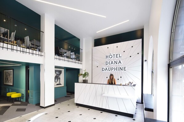 A modern hotel lobby with a reception desk, seating area, and a staircase. - Hotel Diana Dauphine (Strasbourg)