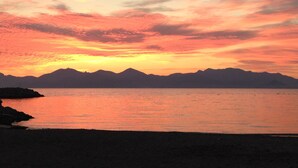 A sunset over a calm sea with mountains in the background. - Hotel Festival (Cannes)