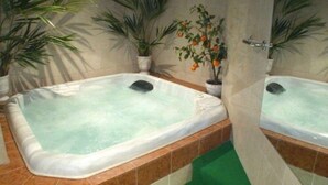 A bathroom with two hot tubs, tiled walls, and potted plants. - Hotel Festival (Cannes)